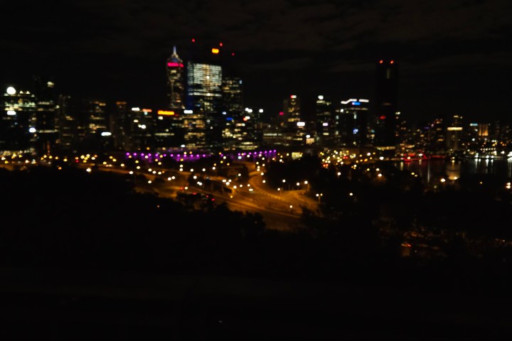 Blurry city skyline at night with colorful lights and a dark sky.