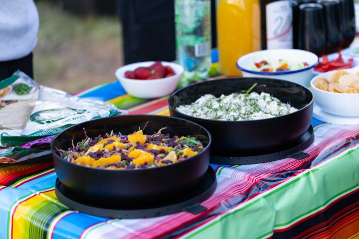 Colorful table with salads, strawberries, drinks, and chips.