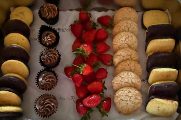 Tray with cookies, chocolate cupcakes, strawberries, and more cookies in neat rows.